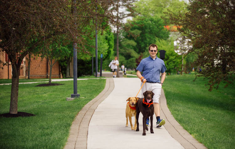 Michael Karchner walks two dogs across campus.